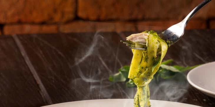 Ein Teller mit einer frisch zubereiteten, grünen Tagliatelle und Hühnchenbrust in einem italienischen Restaurant.