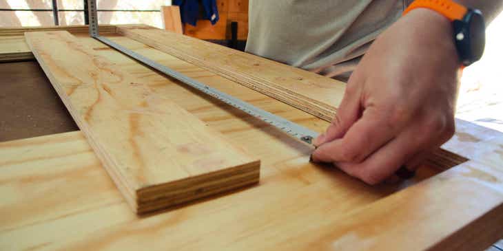 Seorang pria mengukur kayu di bisnis joinery.