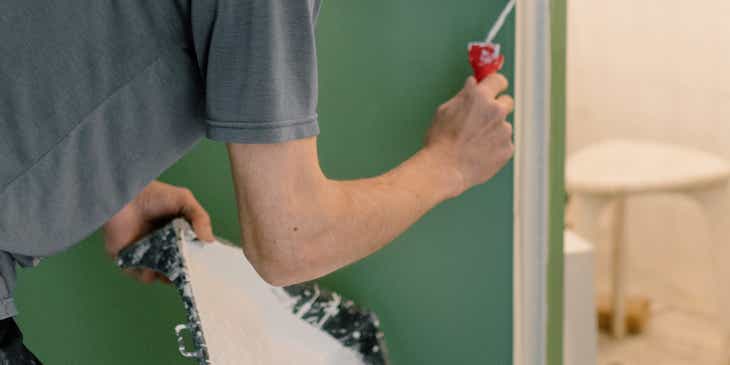 Bir evin duvarını boyayan bir konut hizmeti çalışanı.