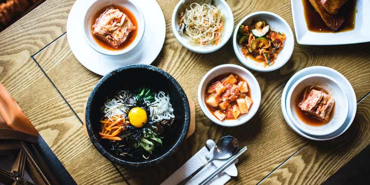 Varios platillos coreanos y cubiertos sobre la mesa en un logo para restaurante coreano.