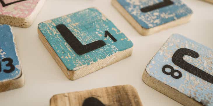 Ein farbiger Holzblock mit dem Buchstaben „L“ liegt neben ähnlichen Blöcken auf einem Tisch.