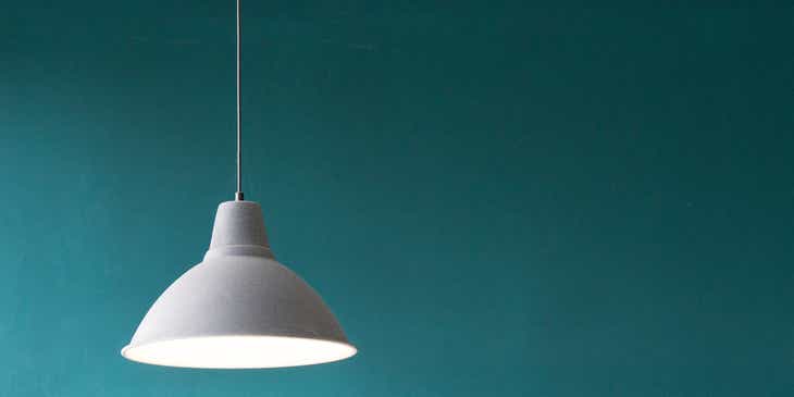 Una lámpara colgante gris sobre un fondo verde.