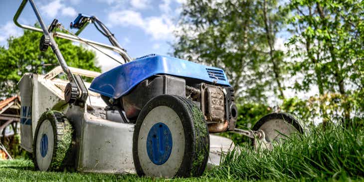 Ein Rasenmäher eines Rasenpflege-Unternehmens steht auf der Rasenfläche.