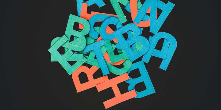A pile of colorful letters for logos displayed on a black surface.