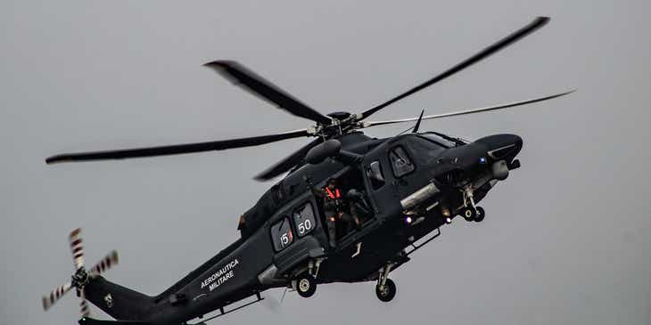 Sebuah helikopter militer sedang terbang mengangkut dua orang.