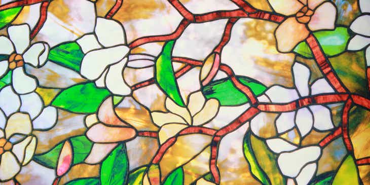 Jendela kaca patri dengan gambar bunga, ranting, dan daun.