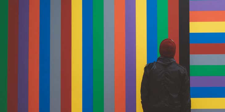Een persoon die naar een muur met diverse kleuren kijkt.
