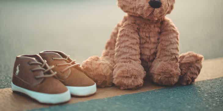Sepasang sepatu kecil di sebelah boneka beruang yang lucu.
