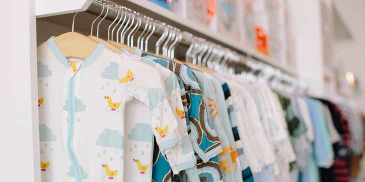 Berbagai pakaian bayi digantung di sebuah rak baju.
