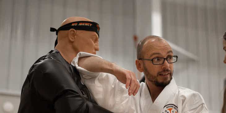 Seorang pelatih mendemonstrasikan teknik self-defense pada sebuah dummy.