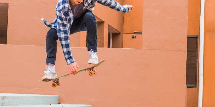 Seorang pemain skateboard melompat dengan skateboardnya di udara.