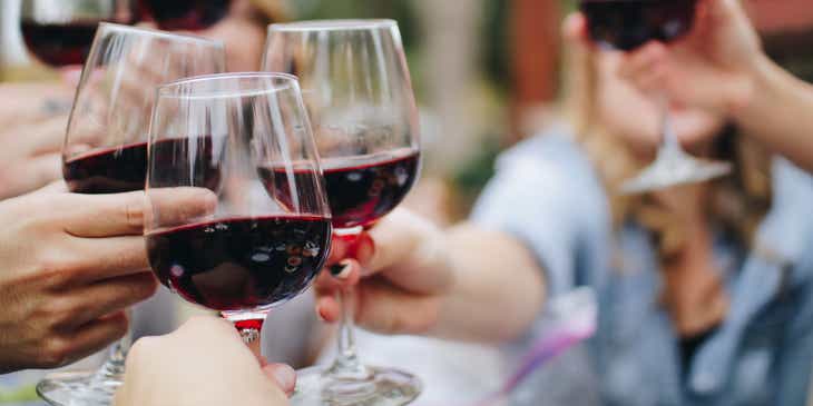Eine Gruppe von Menschen stößt mit einem Glas Rotwein an.