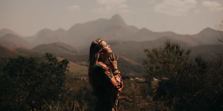 Una mujer orando con mucha fe en un valle.