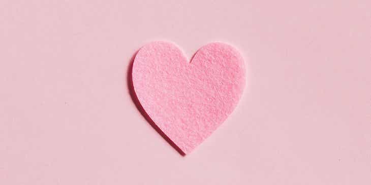 Un cuore di carta rosa sopra un foglio di carta rosa.