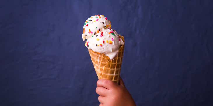Uma mão segurando um cone de sorvete.
