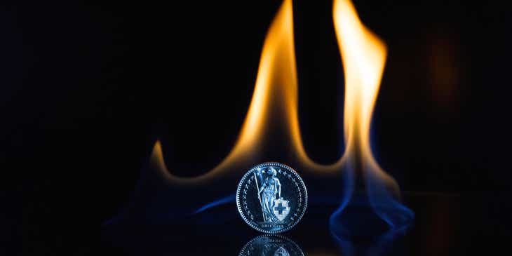 Una moneda plateada en llamas sobre un fondo oscuro en un logo de monedas.