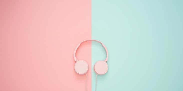 Unos audífonos sobre una pared de tonos gráciles en color rosa y azul pastel.