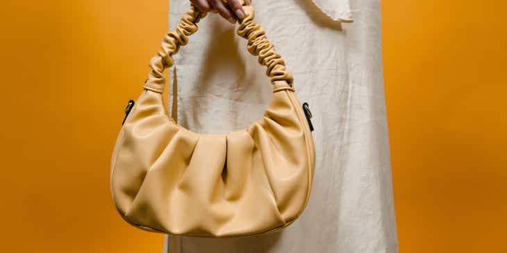 Bolso amarillo siendo sujetado por una mujer con vestido blanco.