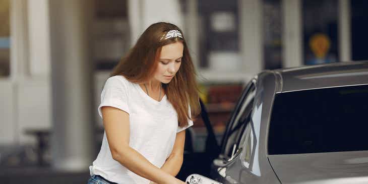 Una mujer cargando gasolina a su auto en un logo para dispensadores de gasolina.