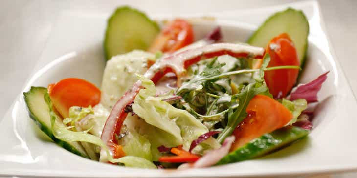 A freshly prepared salad served in a shallow white bowl.