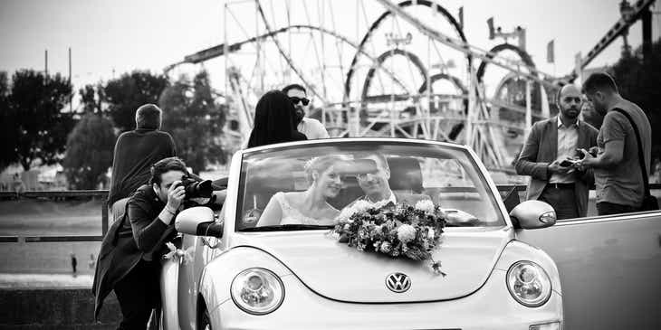 Fotógrafo de bodas tomando una foto de una pareja en un coche, en un logo para fotografía de bodas.