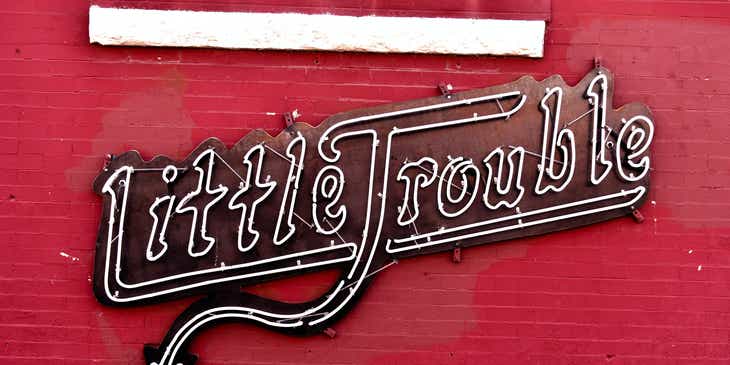 Un letrero de neón que dice: ”Little Trouble”, en un logo travieso.