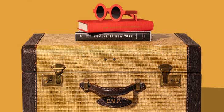 A pair of sunglasses and some books resting on top of a traveler's luggage.
