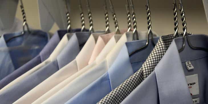 Camisas formales para hombres colgadas en ganchos en un negocio de ropa para hombre.