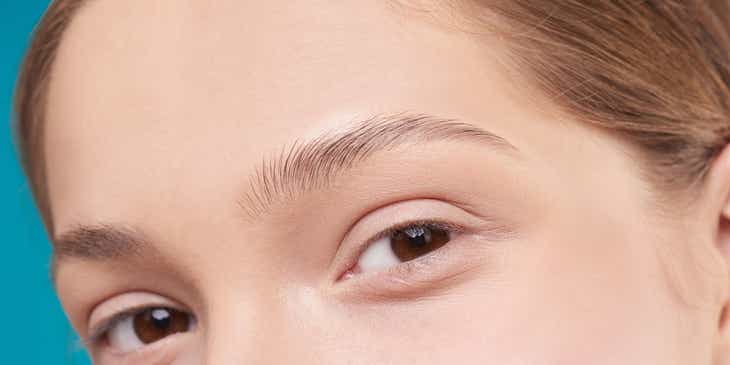 A woman showing off her eyebrows after a microblading session.