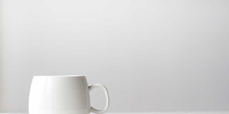 Una taza de cerámica blanca sobre un fondo blanco en un logo minimalista.
