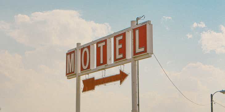 Een rood-wit bord met een pijl die de richting van een motel aangeeft.
