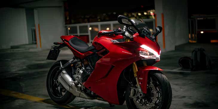 A red and black motorcycle standing in a parking structure.