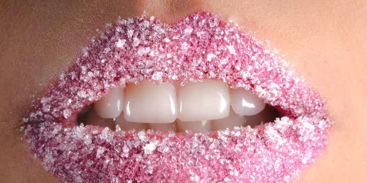 Ein leicht geöffneter, pink geschminkter Frauenmund mit Salzkristallen auf den Lippen.