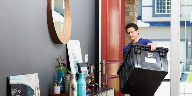 Un empleado traslada las pertenencias de un cliente a un nuevo hogar en un logo para mudanzas.