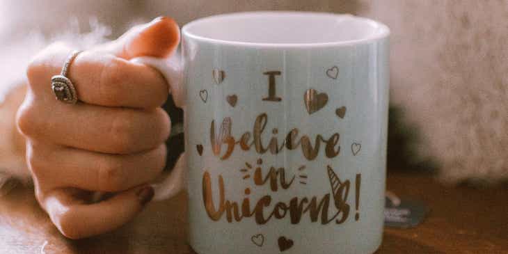 A woman holding a mug that says "I believe in unicorns."