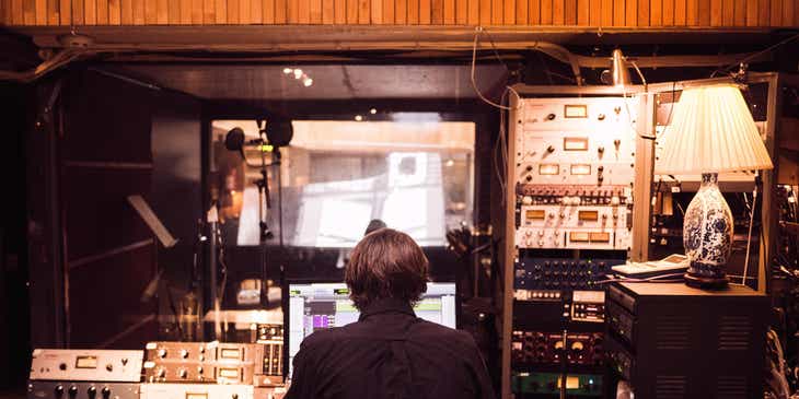 Un productor musical que trabaja en una canción en un estudio, en un logo para compañías de producción musical.