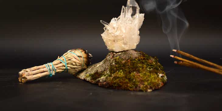 Incense, burning sage, and crystals displayed against a dark backdrop.