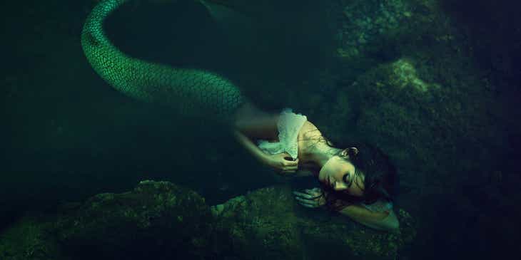 Una sirena mitológica durmiendo bajo el agua en un logo mitológico.