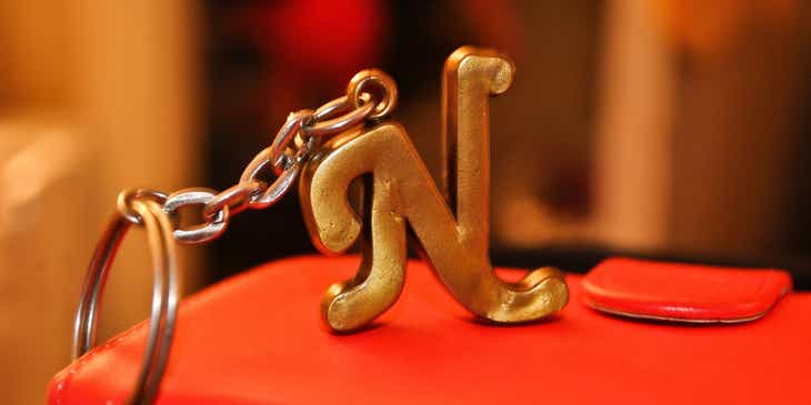 An "N" letterform keychain attached to a red purse.