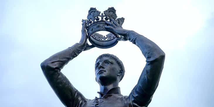 Eine edle Bronzestatue eines Mannes mit der eine dekorative Krone über seinem Kopf hält.
