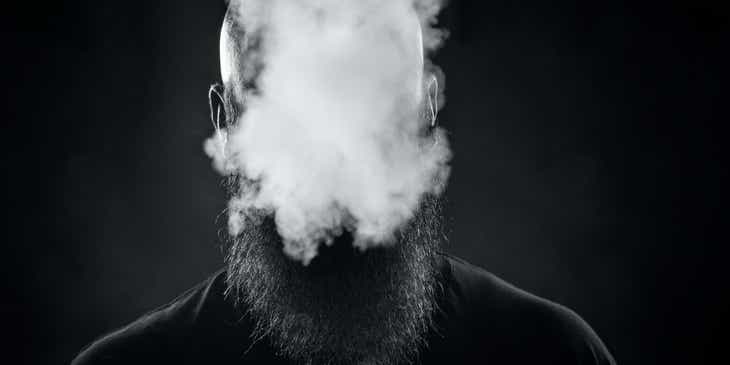 A man's face obscured by a cloud of smoke.