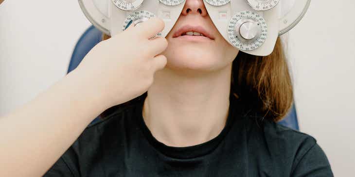 Bir optometrist tarafından gözleri muayene edilen bir kadın.