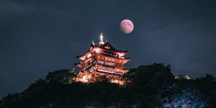Sebuah bangunan oriental di puncak bukit di bawah sinar bulan.