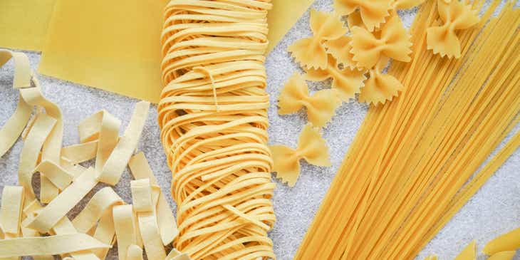 Diverse soorten pasta verspreid over een tafel.