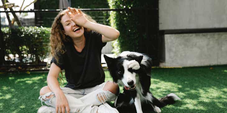 Eine Frau spielt während des Tiersittings mit einem Hund im Garten eines Hauses.