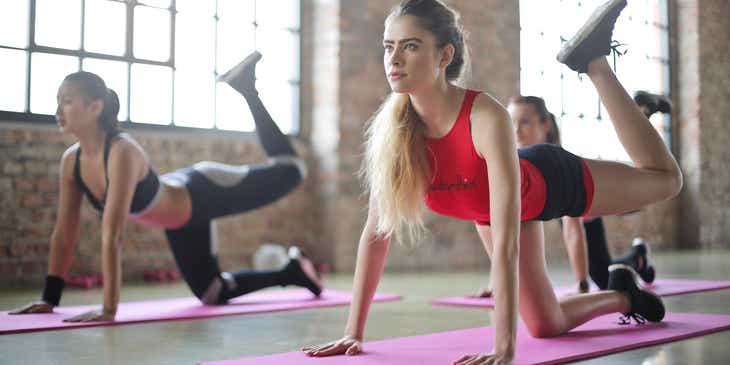 Frauen auf Sportmatten führen Dehnübungen in einem Pilates-Studio durch.