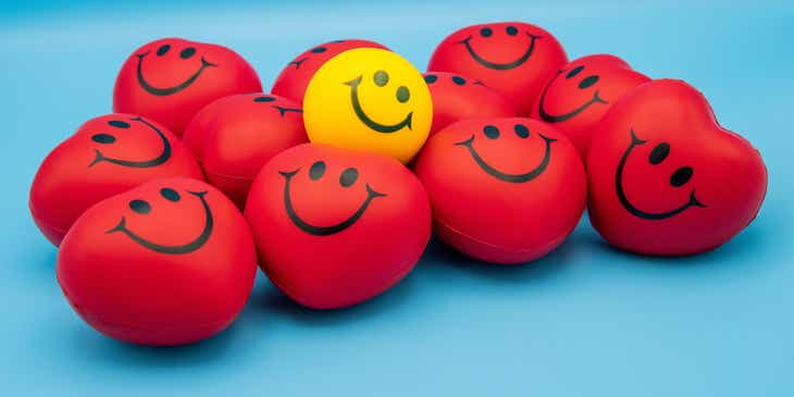 Bolas rojas y amarillas en forma de corazón con caras sonrientes en un logo positivo.