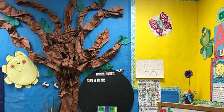 Une salle d'école maternelle avec des images colorées au mur et divers supports pédagogiques dans la pièce.