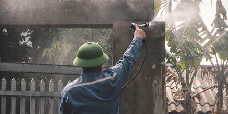 Un uomo che usa una idropulitrice per pulire un cancello a pressione.