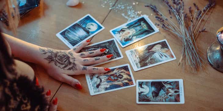 Une main de médium lisant les cartes de tarot sur une table avec de la lavande et des cristaux.